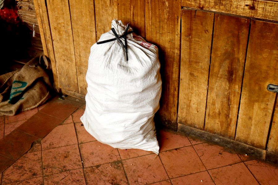 sack or a white plastic sack tied with a black string, with a brown wooden background